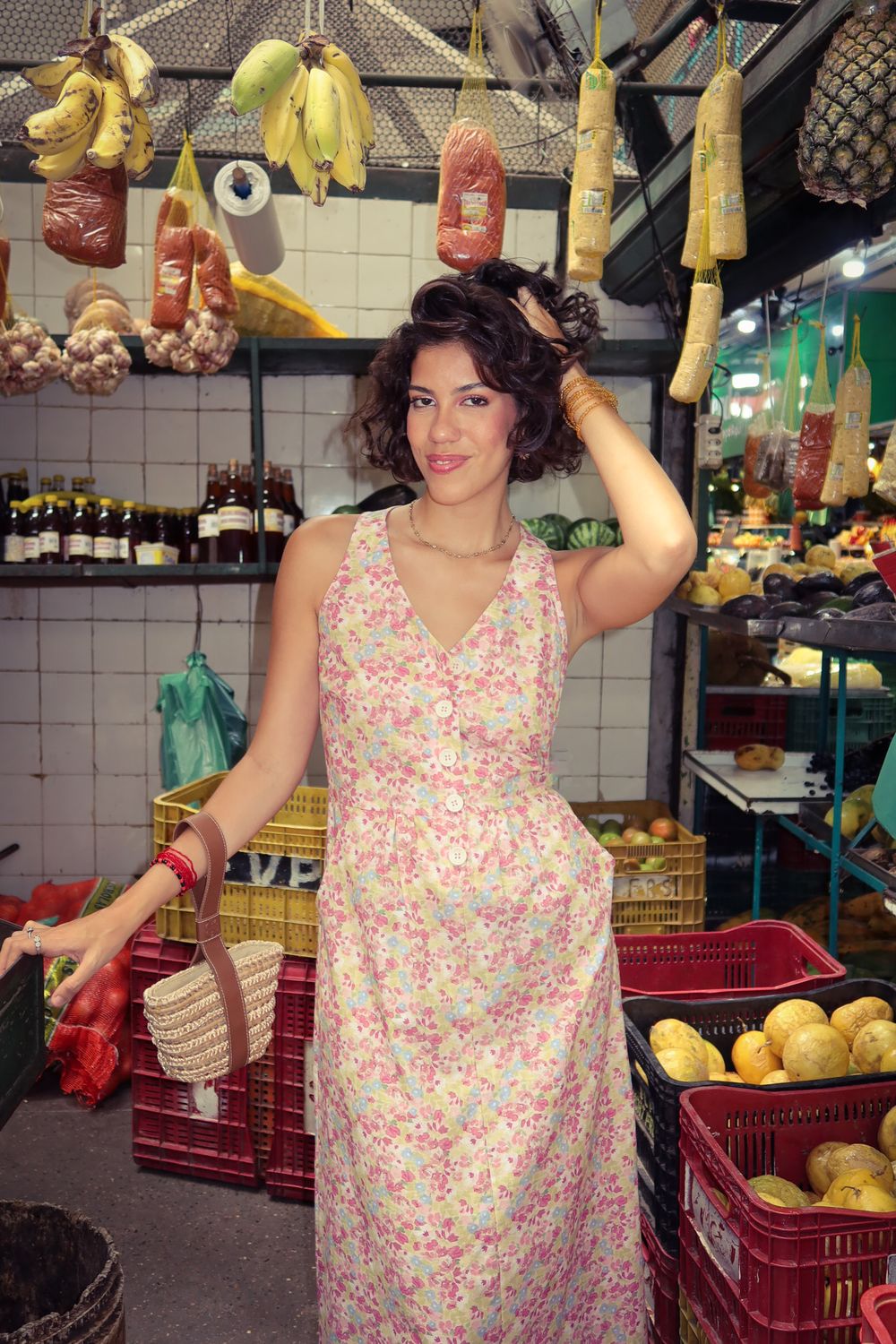 Fernanda Pontes em vestido floral, em meio a barracas de frutas em feira livre