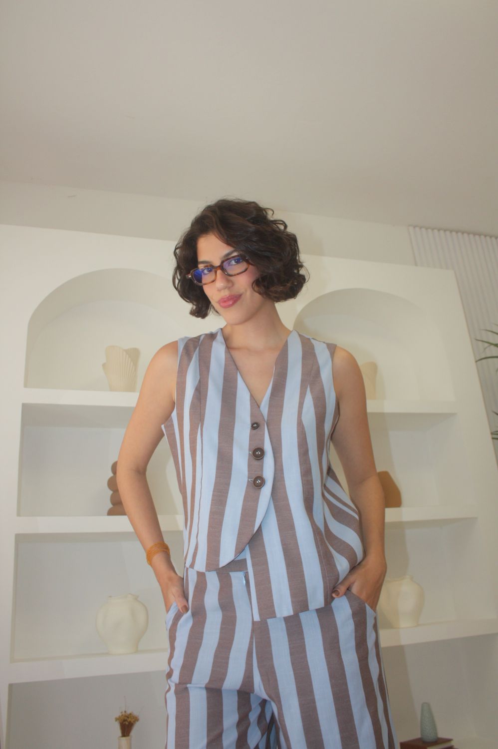 Fernanda Pontes em conjunto listrado, em estante branca arqueada