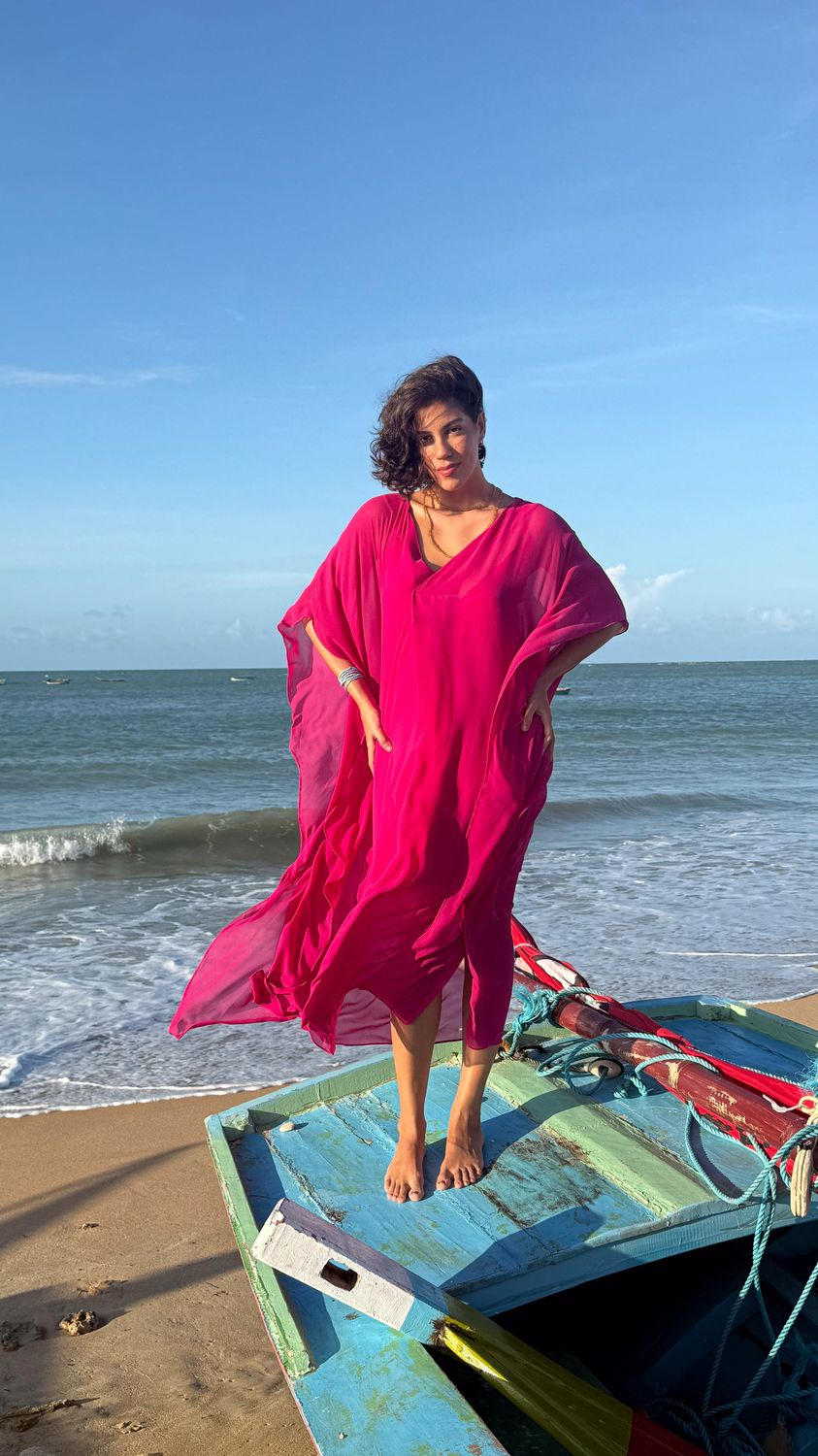 Fernanda Pontes em vestido pink em cima de barco de pesca colorido na praia